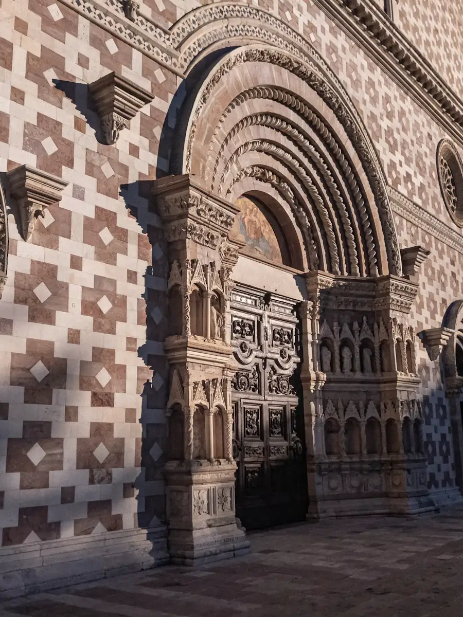 Facciata in pietra bianca e rosa della basilica di Santa Maria di Collemaggio all’Aquila