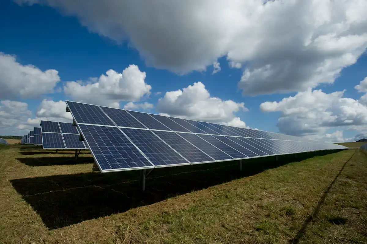 Fila di moduli fotovoltaici in un prato sotto un cielo con nuvole